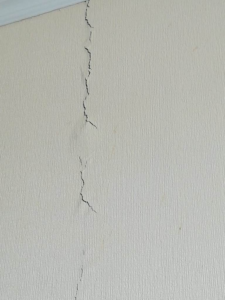Квартира трещины. Трещина в стене в квартире. В новостройке трещина в стене в квартире. Вертикальная трещина на белой стене. Аварийные трещины в квартире.